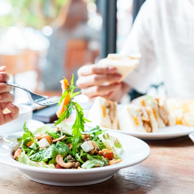 People enjoying lunch with a close up on someone's salad