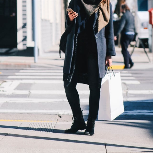 A woman standing on the sidewalk using her phone