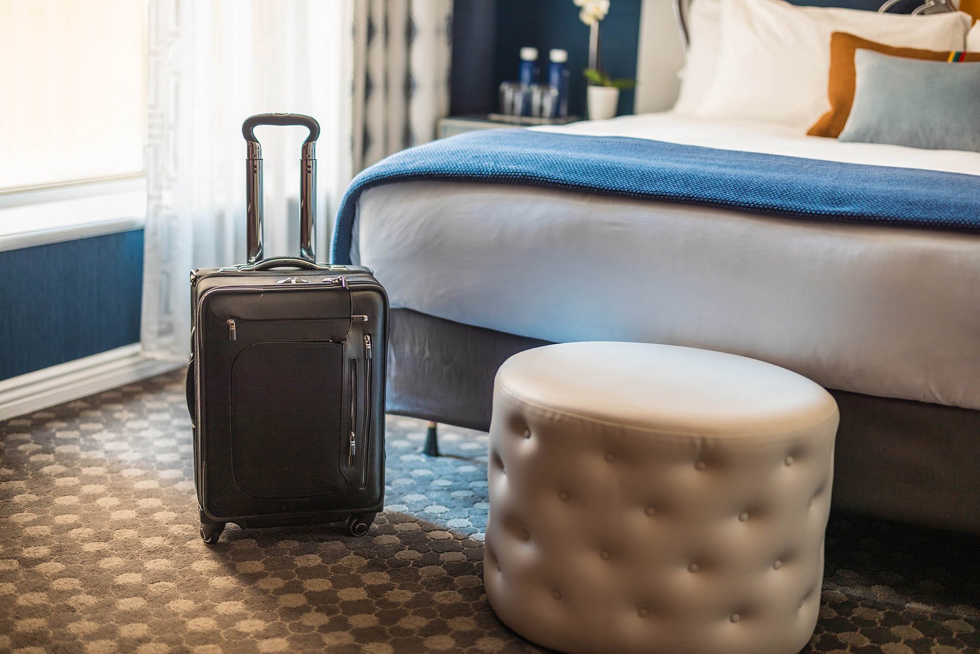 Luggage sitting next to a chair in front of a bed at The Marker