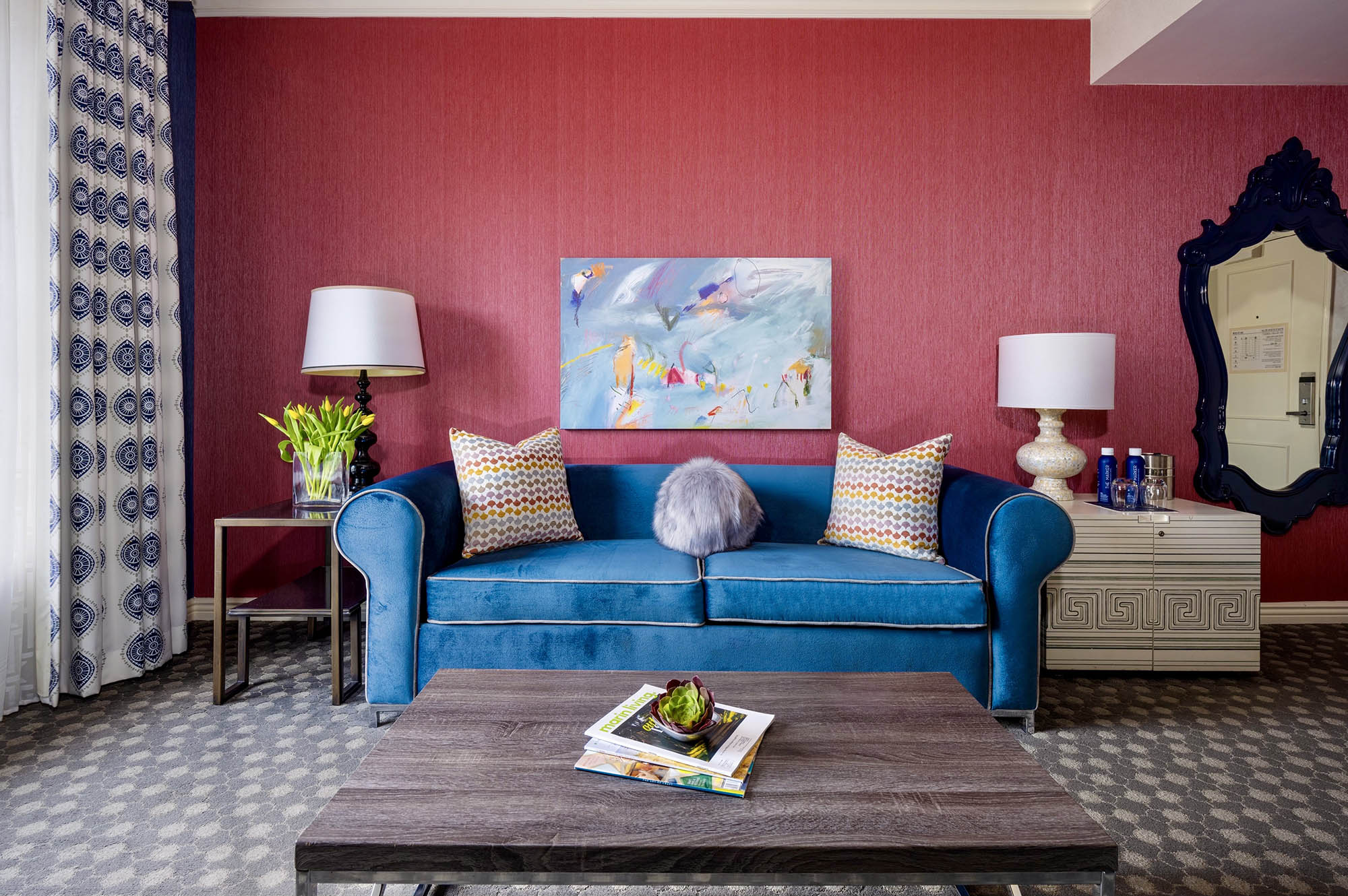 A large blue couch sitting in front of a red wall at The Marker